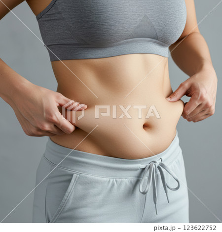 スポーツブラとレギンスを着用してお腹の脂肪をつまむ女性のクローズアップ（AI生成画像） 123622752