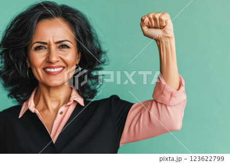 Mature middle eastern woman in office with raised fist of empowerment, strength and women solidarity, International Womens Day concept 123622799