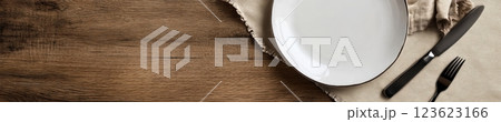 White empty plate with silver cutlery on a rustic wooden table, beige napkin in a diamond layout. Natural lighting and warm wood tones create a cozy, inviting atmosphere with wide copyspace. White empty plate with silver cutlery on a rustic wooden table, beige napkin in a diamond layout. Natural lighting and warm wood tones create a cozy, inviting atmosphere with wide copyspace. 123623166
