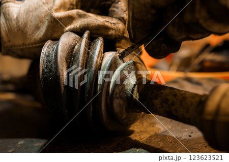 Close-up of mechanic hands repairing and inspecting automotive CV axle shaft joint boot in workshop conditions 123623521