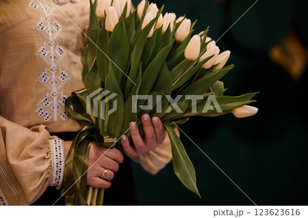 Elegant Woman Holding a Bouquet of Cream Tulips in Traditional Dress 123623616