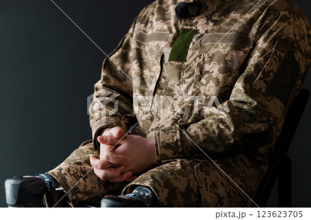 A Soldier in Military Uniform with Advanced Bionic Leg Prosthesis Sitting Thoughtfully 123623705