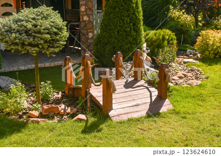 A wooden bridge in the courtyard on a green lawn A wooden bridge in the courtyard on a green lawn 123624610