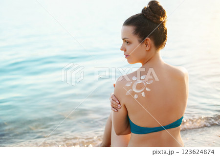Sun Cream. Skin and Body Care. Woman Applying Sun Cream on Tanned Shoulder In Form Of The Sun. Sun Protection.Girl Using Sunscreen to Skin. 123624874