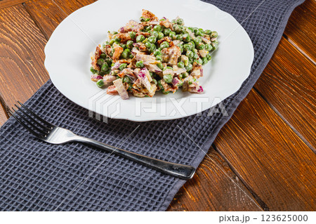 Colorful salad featuring peas, chicken, and dressing on a rustic table 123625000
