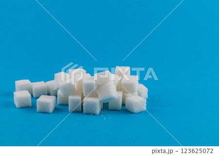 Cubes of white sugar stacked on a bright blue background Cubes of white sugar stacked on a bright blue background 123625072