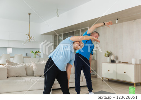 Fitness training. Senior mature healthy fit couple doing sports exercise at home. Mid age husband wife have training workout. Health care healthy lifestyle. Workout rehabilitation for old man woman 123626051