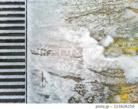 Soap sud waste flows to floor drain grid in car washing garage, close-up. 123626250