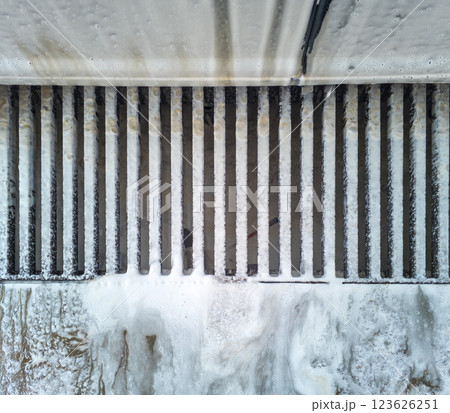 Soap sud waste flows to floor drain grid in car washing garage, close-up. 123626251