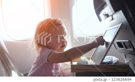 Little girl playing with folding tray table on airplane 123626694