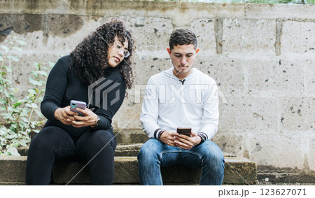 Suspicious person spying on her boyfriend phone. Jealous girl spying on her boyfriend cell phone, suspicious girlfriend spying on her boyfriend cell phone 123627071