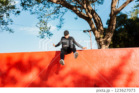 Young man doing jumping parkour at sunset. Guy doing wall jump parkour, Artistic image of man doing parkour Young man doing jumping parkour at sunset. Guy doing wall jump parkour, Artistic image of man doing parkour 123627073