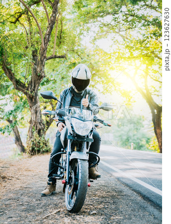 Motorcyclist in safety helmet with thumb up on the road. Biker wearing safety helmet with thumb up on the road Motorcyclist in safety helmet with thumb up on the road. Biker wearing safety helmet with thumb up on the road 123627630