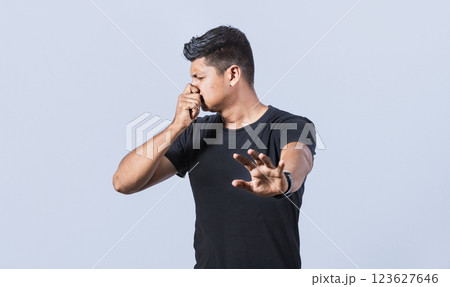 Confused unhappy man grabbing nose with fingers and stretching hand out feeling disgusted, Annoyed man covering his nose with a gesture of displeasure Confused unhappy man grabbing nose with fingers and stretching hand out feeling disgusted, Annoyed man covering his nose with a gesture of displeasure 123627646