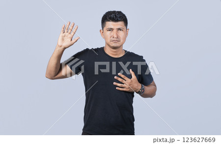 Honest man raising his hand, a A guy raising his hand swearing, Man swearing honesty and devotion, young man raising a hand promising something 123627669