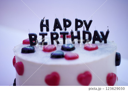 Birthday cake decorated with black candles shaped Happy Birthday inscription, hearts shaped jellies. 123629030