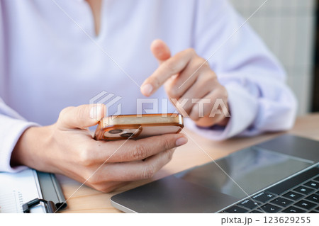 Hands interacting with a smartphone and laptop, showcasing technology use in a professional environment. 123629255