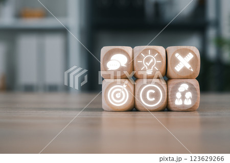 Wooden blocks with corporate icons representing business identity, branding, and strategy in a modern office setting. Wooden blocks with corporate icons representing business identity, branding, and strategy in a modern office setting. 123629266