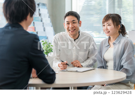 ショールーム・商談スペースで話を聞く夫婦と接客するビジネスマン 123629428