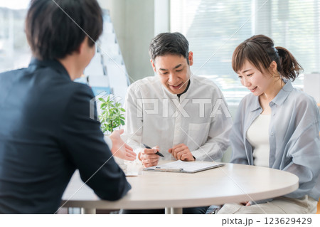 ショールーム・商談スペースで話を聞く夫婦と接客するビジネスマン 123629429