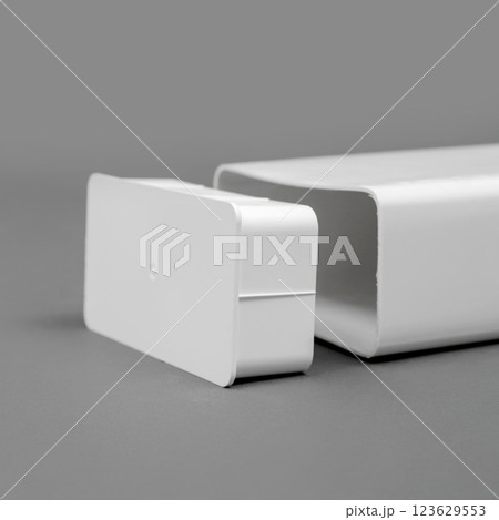 White plastic pipe with a plug on a gray background. Rectangular shape. White plastic pipe with a plug on a gray background. Rectangular shape. 123629553