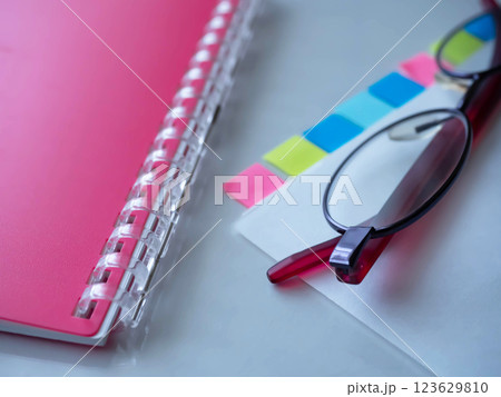テーブルに置かれた書類と手帳とメガネ 123629810