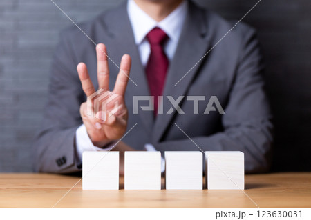 4つの白い木のブロックと3本指を立てるミドル男性ビジネスマン 123630031