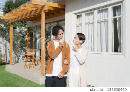 家のまえで考え事をする夫婦 家のまえで考え事をする夫婦 123630489
