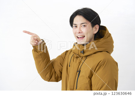 ダウンジャケットを着た男性　左側を指差す　白背景 123630646
