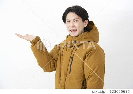 ダウンジャケットを着た男性 左側を手のひらで指す 白背景 ダウンジャケットを着た男性 左側を手のひらで指す 白背景 123630656
