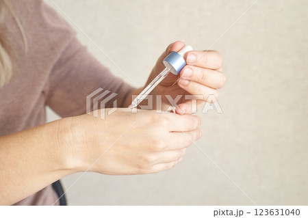 Young caucasian female applying skincare serum with dropper on hand Young caucasian female applying skincare serum with dropper on hand 123631040