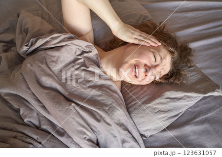 Caucasian adult female waking up in bed with a headache or migraine holding head Caucasian adult female waking up in bed with a headache or migraine holding head 123631057