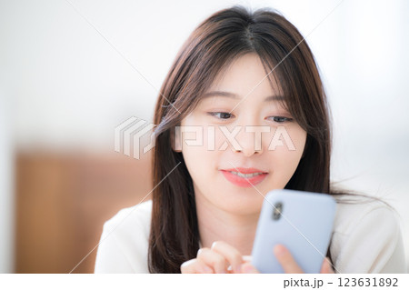 部屋でうつ伏せでスマホを見る若い女性のクローズアップ 123631892