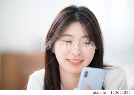 部屋でうつ伏せでスマホを見る若い女性のクローズアップ 部屋でうつ伏せでスマホを見る若い女性のクローズアップ 123631893
