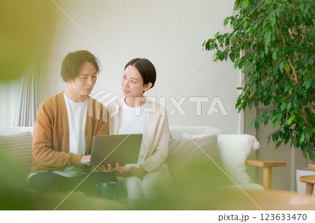 ソファに座ってパソコンを見る夫婦 123633470
