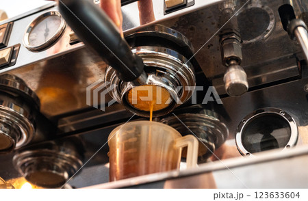 An Espresso machine making an espresso with a "naked" portafilter, directs high-pressure hot water through the coffee puck. 123633604