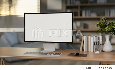 The white screen computer on the wooden table with books and decors in the bedroom or living room. 123633639