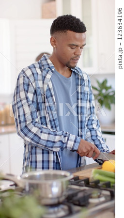 Vertical image of african american man chopping vegetables in kitchen 123634196