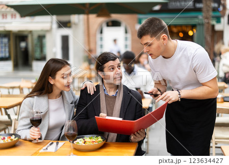 Couple husband and wife ordering from boyfriend waiter in restaurant Couple husband and wife ordering from boyfriend waiter in restaurant 123634427
