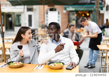 Interethnic couple happily chatting while sitting on the terrace of a restaurant Interethnic couple happily chatting while sitting on the terrace of a restaurant 123634450