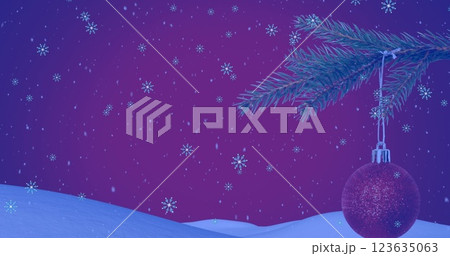 Image of snow falling over christmas tree with red bauble in winter scenery 123635063