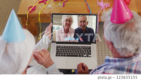 Merry christmas text over senior couple having a imagecall on laptop during christmas Merry christmas text over senior couple having a imagecall on laptop during christmas 123635155