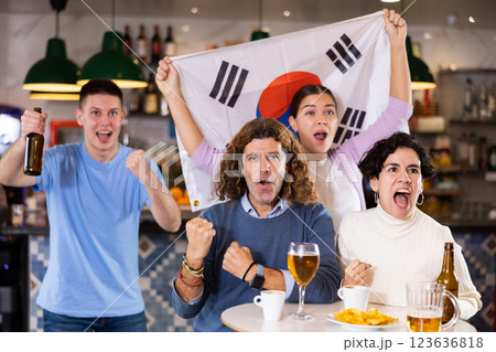 Group of happy friends with flag of South Korea celebrating victory of their favorite team in beer bar Group of happy friends with flag of South Korea celebrating victory of their favorite team in beer bar 123636818