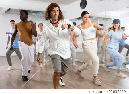 Excited sporty multiracial people practicing new movements steps during dancing training in studio 123637039
