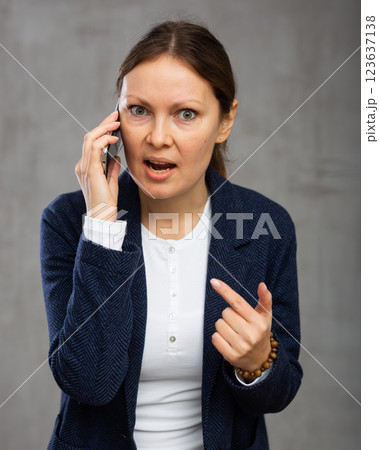 Indignant adult woman in jacket talking on phone Indignant adult woman in jacket talking on phone 123637138