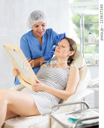 Cosmetologist examine patients contour face after lifting oval of face and palpate cheekbones 123637340