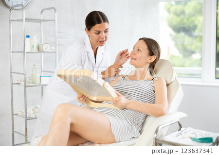 After examination, woman cosmetologist and female patient discuss results of acne treatment 123637341