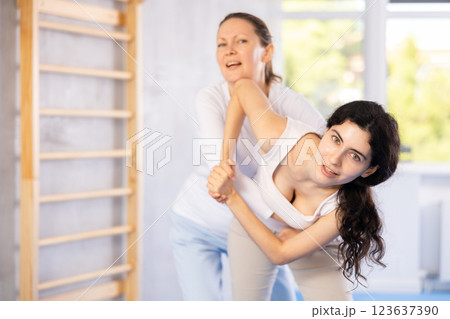 Woman learns to do a power grip with a trainer during a self-defense lesson in gym Woman learns to do a power grip with a trainer during a self-defense lesson in gym 123637390