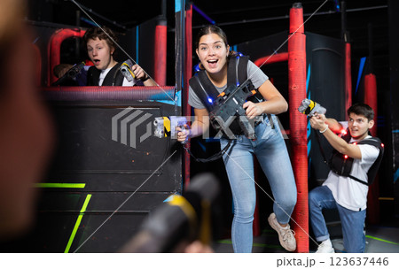 Two guys and one girl running and dodging while playing lasertag Two guys and one girl running and dodging while playing lasertag 123637446