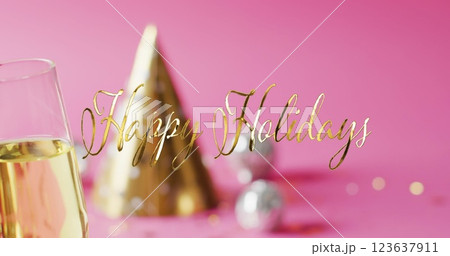 Image of happy holidays text over party hat and champagne glass Image of happy holidays text over party hat and champagne glass 123637911